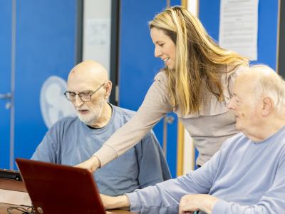 three people looking at a laptop