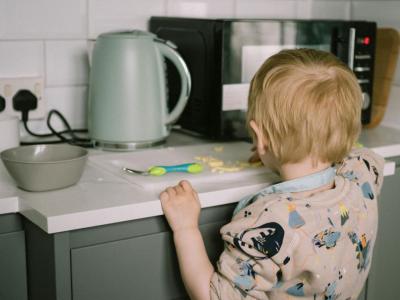 young child in a kitchen cuttig cheese